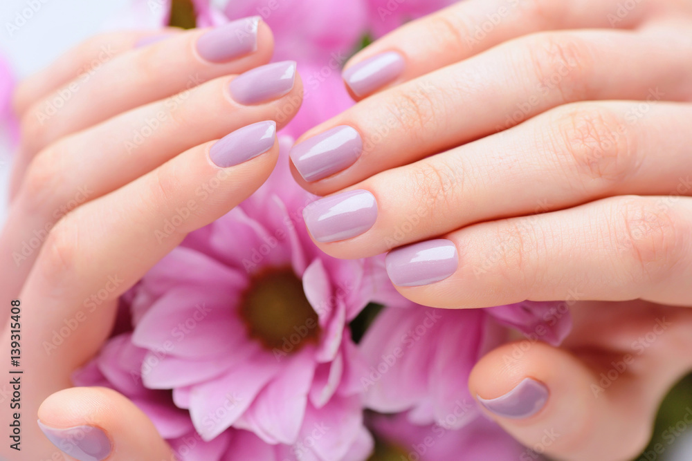 Hands of a woman with pink manicure on nails and pink flowers