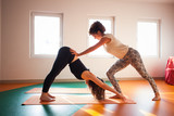 yoga instructor assisting student in exercis