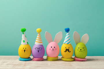 Easter holiday concept with cute handmade eggs, bunny, chicks and party hats