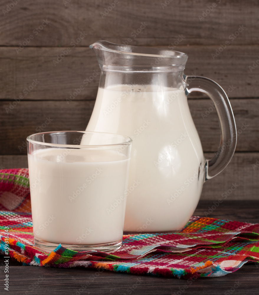 jug and glass of milk on a wooden background jug and glass of milk on a wooden background