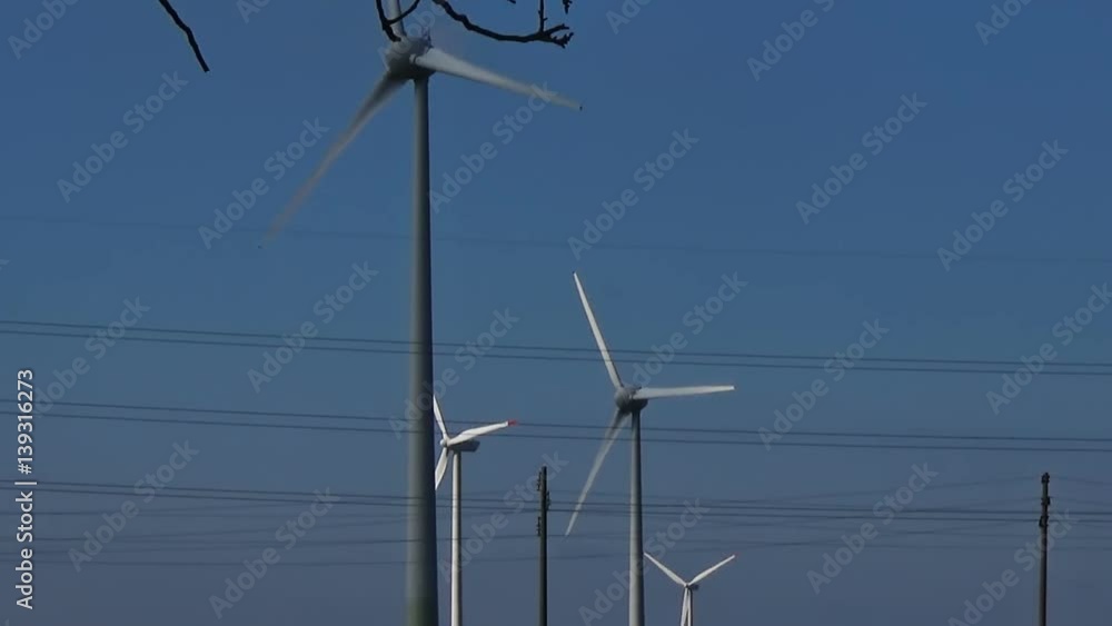 Slow motion seamless loop moving background of four wind turbines on the blue sky with white clouds producing and generating clean eco green renewable electrical energy and electricity power some Slow motion seamless loop moving background of four wind turbines on the blue sky with white clouds producing and generating clean eco green renewable electrical energy and electricity power some