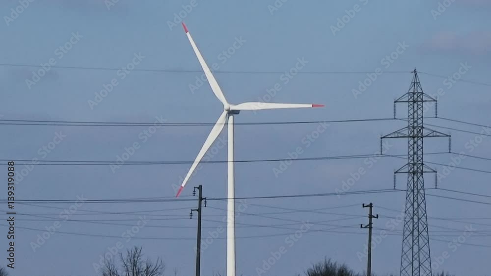 Slow motion seamless loop close up shot of white wind turbine with red tips at blue sky with white clouds generating clean renewable eco electrical energy and power grid lines and poles in the sunny Slow motion seamless loop close up shot of white wind turbine with red tips at blue sky with white clouds generating clean renewable eco electrical energy and power grid lines and poles in the sunny