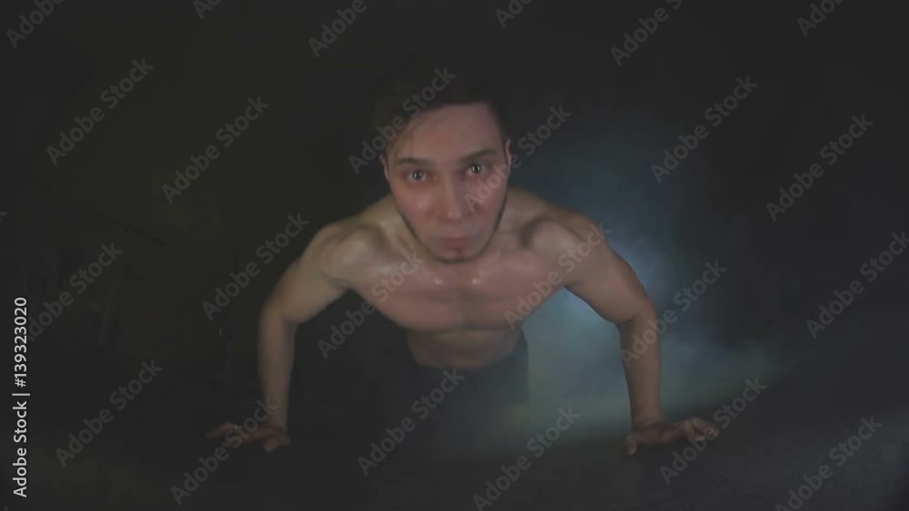 Young man pushes up from wooden floor in gym Young man pushes up from wooden floor in gym