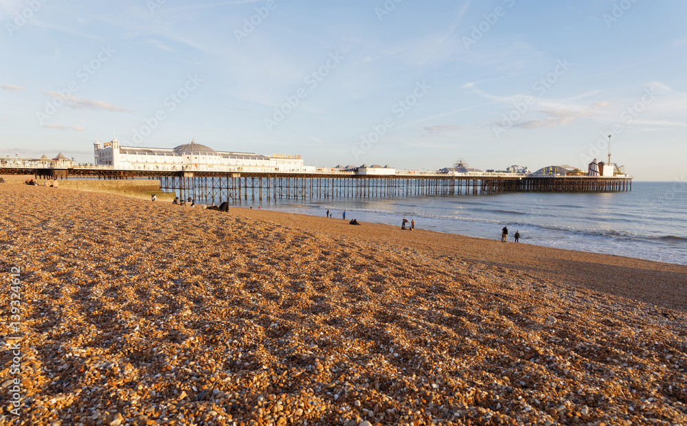 Brighton pier at warm evening light, distant people walking on the beach