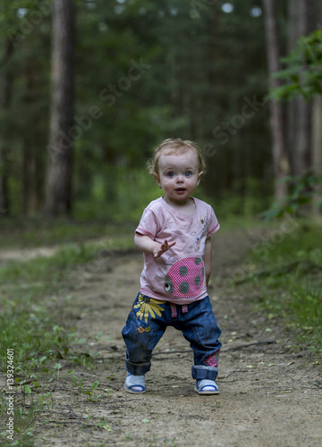 Little cute baby make his first steps on the forest road.