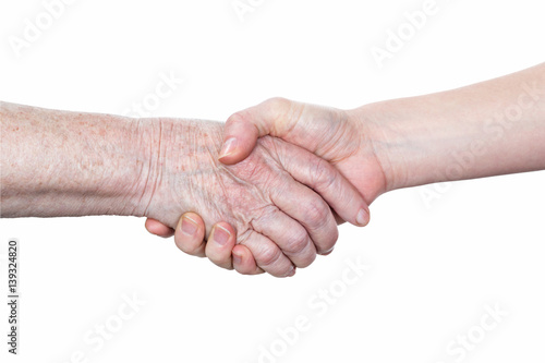 Handshake between an old woman with a wrinkled hand and a young woman isolated on white background