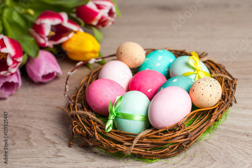 Easter composition of the branches, cakes, tulips colored eggs cooked for the holiday on the wooden background 