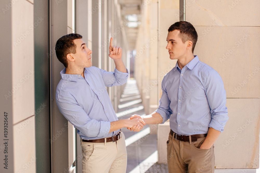 Fototapeta premium Two businessman shaking hads to each other with street city blur background