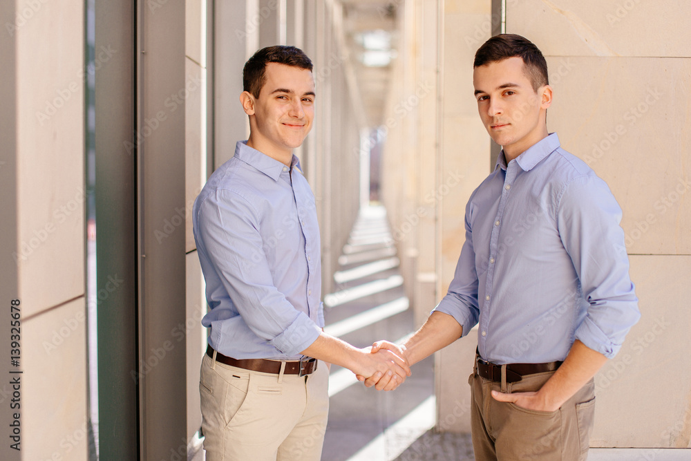 Two businessman shaking hads to each other with street city blur background Two businessman shaking hads to each other with street city blur background