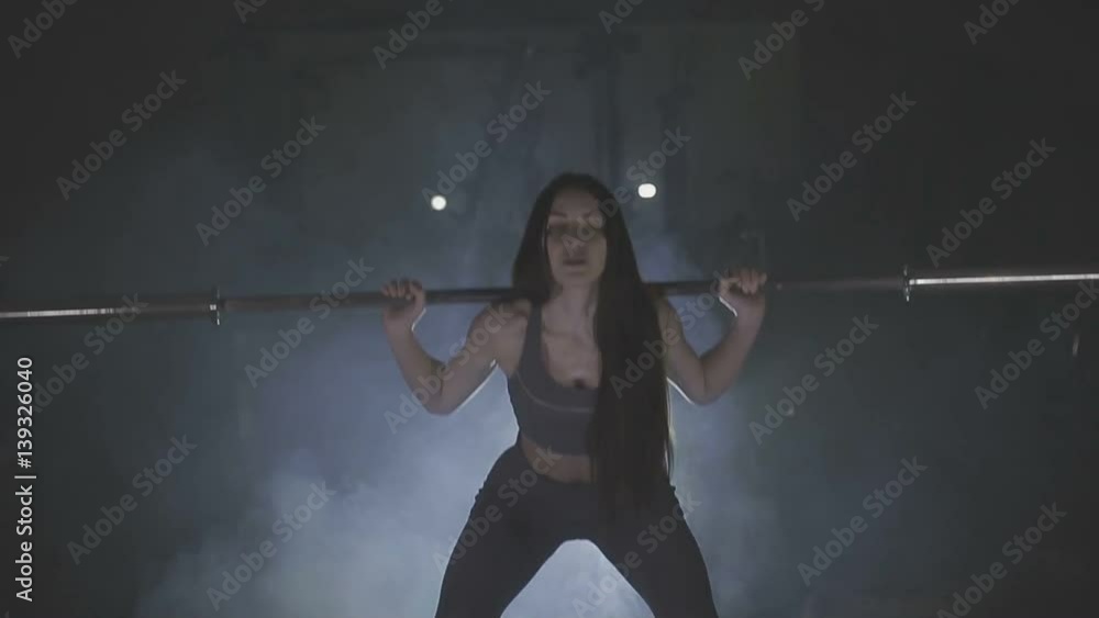 Full length image of a young woman testing her strength by holding a barbell with heavy weights on her shoulders as she squats Full length image of a young woman testing her strength by holding a barbell with heavy weights on her shoulders as she squats