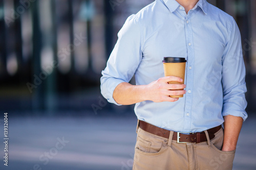 Businessman holding his coffee or tea drink on blur background photo