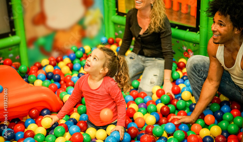 Quadro em tela Diverse culture parents playing with their daughter inside ball pit swimming poo