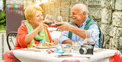 Happy senior couple cheering with red wine in italian restaurant outdoor