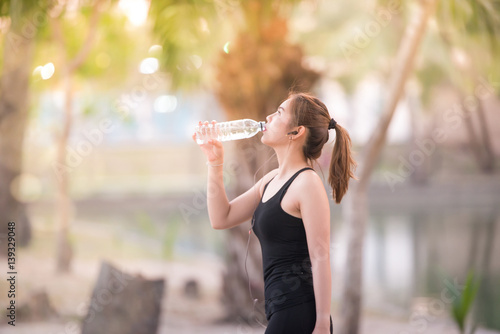 Asian young Fitness woman drinking water after jogging