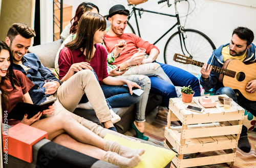 Group of trendy friends having fun in home living room playing music