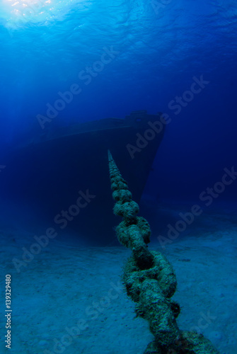 The bow or front end of a sunken war ship as she sits peacefully at the bottom of the sea. underneath the surface the deep blue water is calm for the final resting place of this vessel 