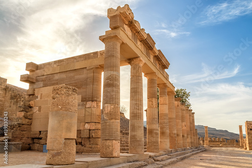 Colonnade with portico main temple of Lindos Rhodes on the background of sunset clouds and the sun