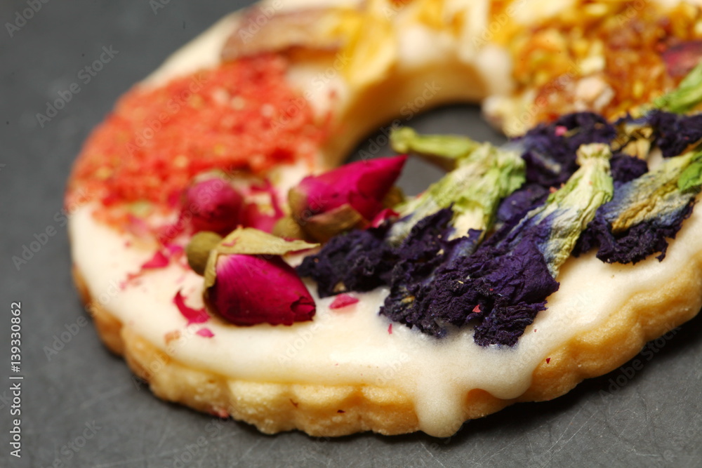 The cookie with flower topping put on slate board represent the bakery and pastry concept related idea. The cookie with flower topping put on slate board represent the bakery and pastry concept related idea.