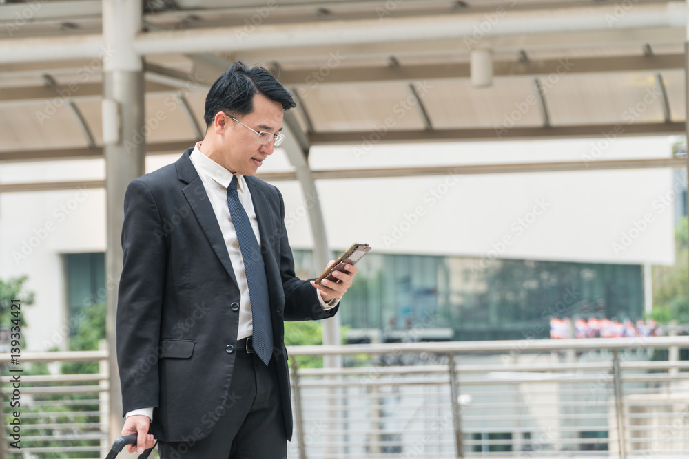 Middle-aged businessman looking smart phone in modern city. Middle-aged businessman looking smart phone in modern city.