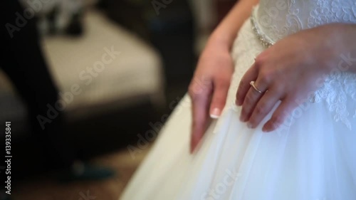 Closeup : Lace white wedding dress with bride's hands.