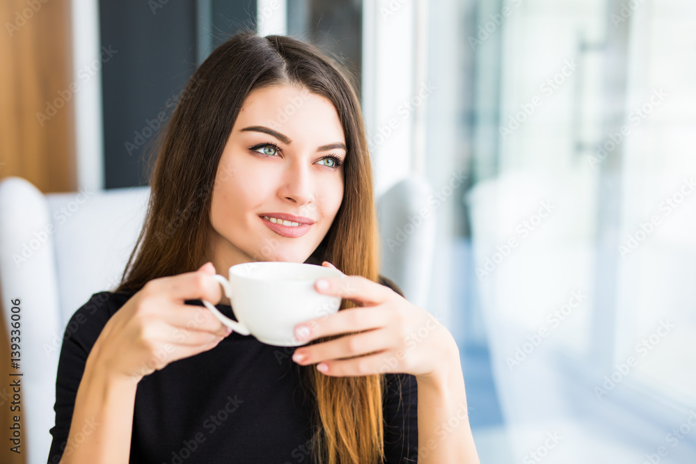 beautiful young woman drinking coffee look in window