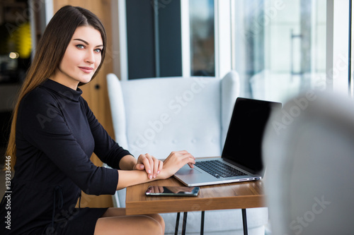 Side view of a young businesswoman using laptop in cafe