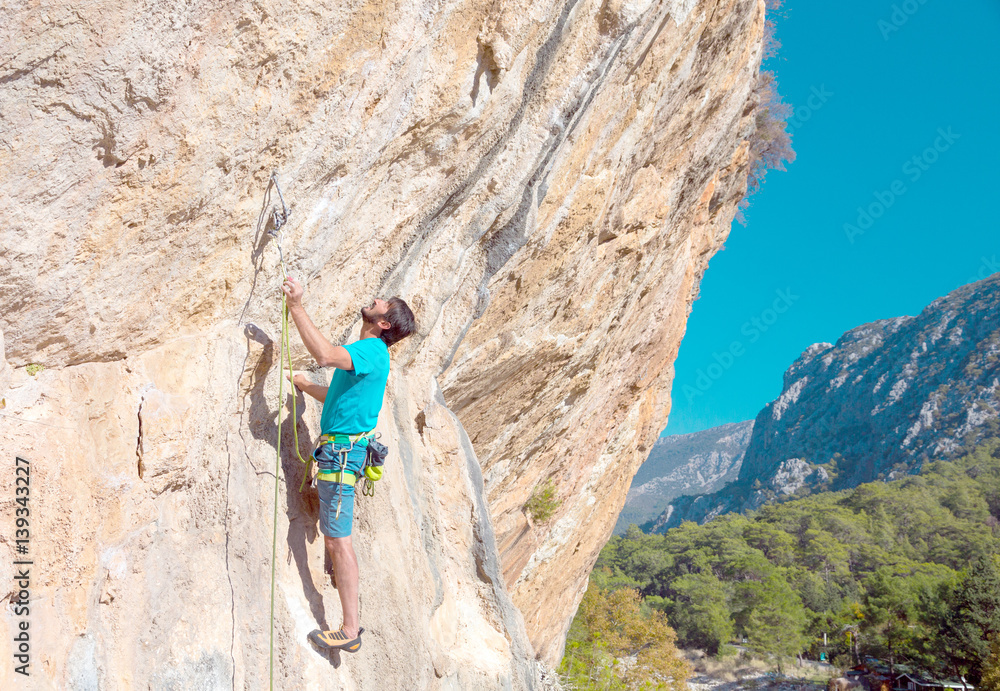 Fototapeta premium Mature male Climber making Move on vertical Rock