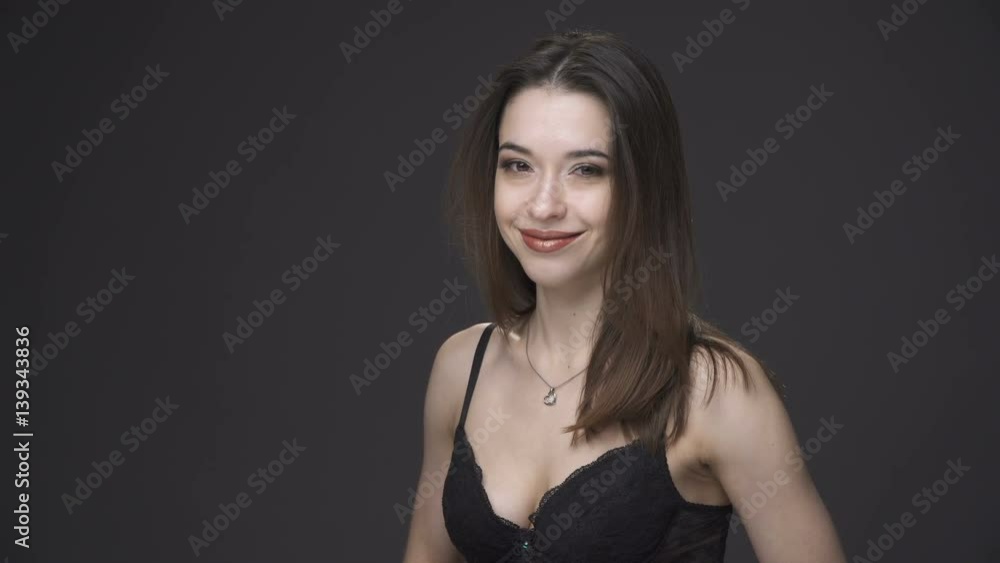 Sexy woman in black underwear turning the head and smiling, gray background Sexy woman in black underwear turning the head and smiling, gray background