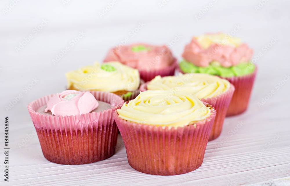Tasty cupcakes on bright background. vanilla cupcakes with pink and yellow cream, selective focus