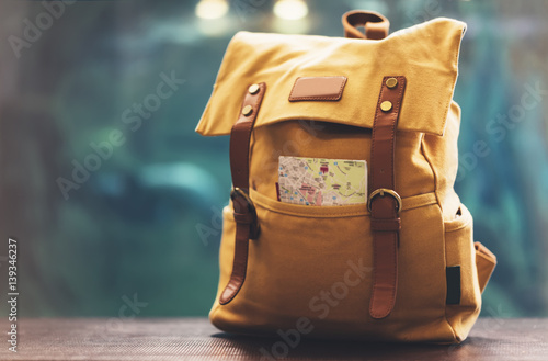 Hipster yellow backpack and map closeup. View from front tourist traveler bag on background blue sea aquarium. Person hiker visiting oceanarium museum in Barcelona on backdrop, blank blurred mockup photo