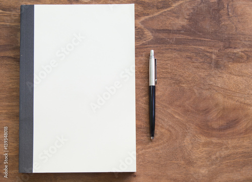 Notebook with pen on wooden table, business concept.