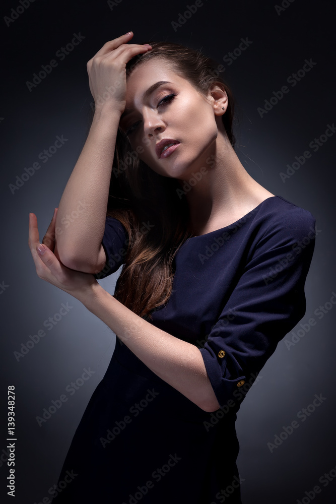 Creative portrait of a girl with a hard light and shadows in a blue dress and evening makeup.