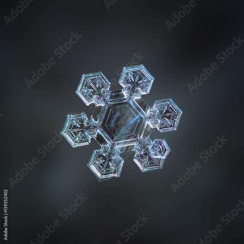 Snowflake glitters on dark cyan blur background. This is macro photo of real snow crystal  medium size star plate with six short arms  containing complex inner pattern  and big central hexagon.