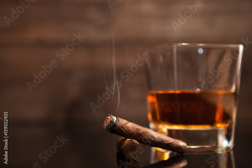 Smoking cigar and glass of whiskey in the background photo