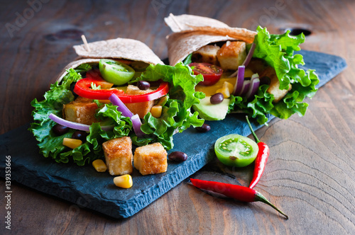 Tortilla wrap or burrito with tofu, greens, and vegetables, vegetarian healthy food, toned image