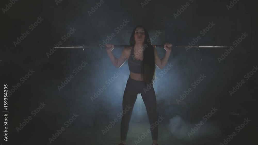 Full length image of a young woman testing her strength by holding a barbell with heavy weights on her shoulders as she squats Full length image of a young woman testing her strength by holding a barbell with heavy weights on her shoulders as she squats