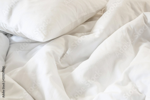 white pillow on bed and with wrinkle messy blanket in bedroom, from sleeping in a long night.