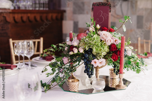 Wedding table decoration with the red, pink flowers and candles