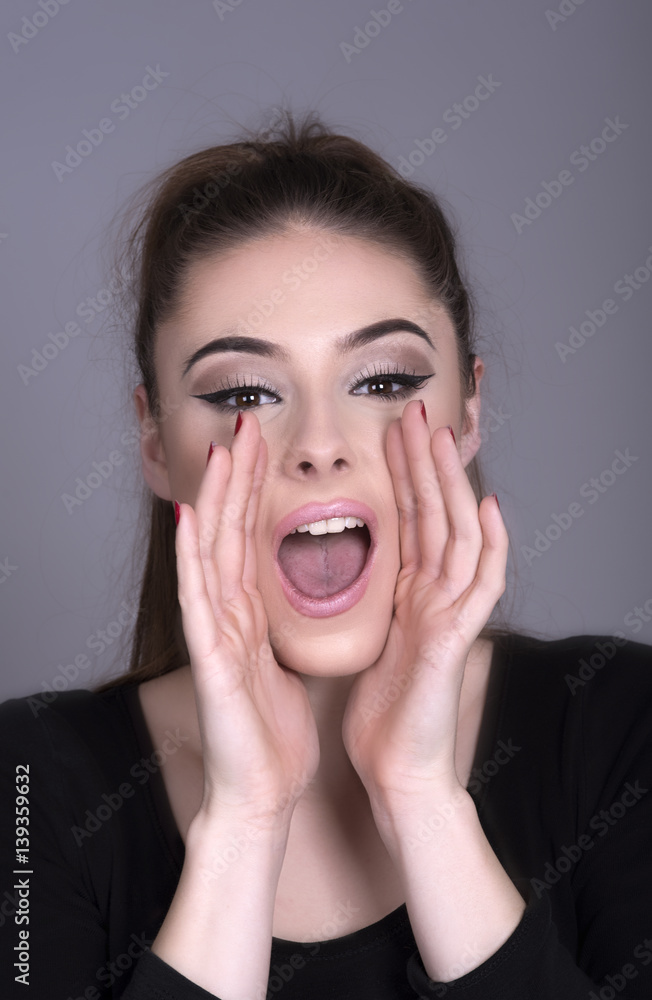 Young woman shouting with hands cupped around the mouth Young woman shouting with hands cupped around the mouth