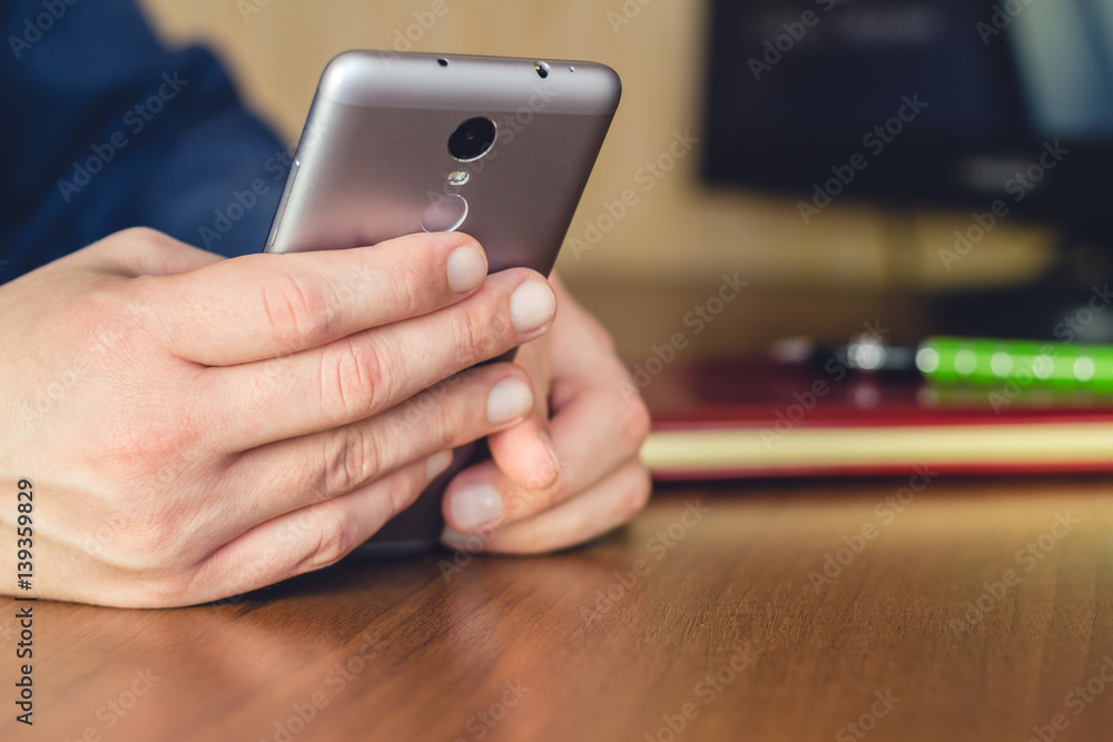 Formal wear, man hands at the desk using aluminum smartphone, selective focus. Formal wear, man hands at the desk using aluminum smartphone, selective focus.