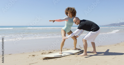 Canvas Print The instructor explains the position to the woman standing on a surfboard in Tarifa beach, Cadiz, Spain
