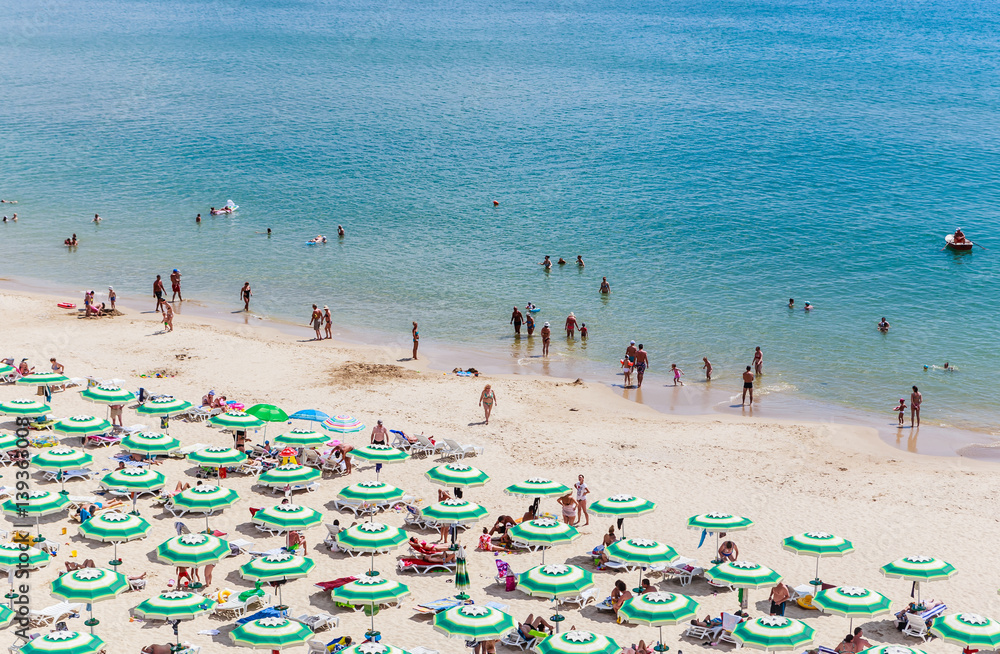 The Black Sea shore, blue clear water, beach with sand, umbrellas and sunbeds. Albena, Bulgaria The Black Sea shore, blue clear water, beach with sand, umbrellas and sunbeds. Albena, Bulgaria
