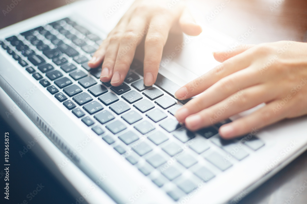 Cropped close up shot of woman's hands typing on keyboard while chatting using computer laptop sitting at wooden table. Human, leisure and modern technology concept. Film effect. Cropped close up shot of woman's hands typing on keyboard while chatting using computer laptop sitting at wooden table. Human, leisure and modern technology concept. Film effect.