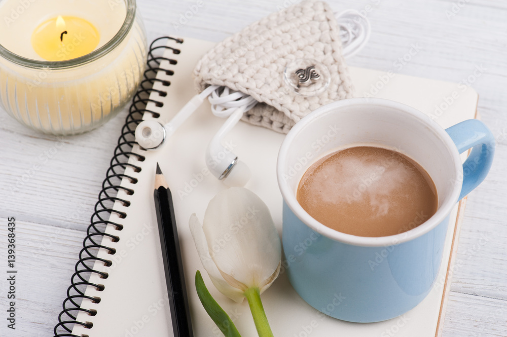 Open notebook, coffe, candle, earpods and tulip