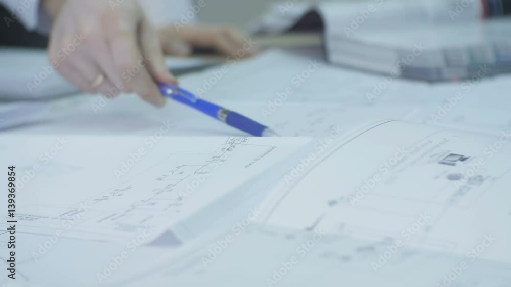 Closeup Man Shows Schemes with Pen on Big White Paper Closeup Man Shows Schemes with Pen on Big White Paper