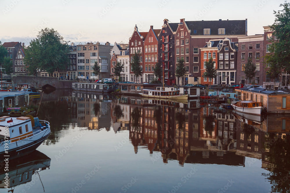 Traditional old buildings and canal with private boats in Amsterdam, the Netherlands