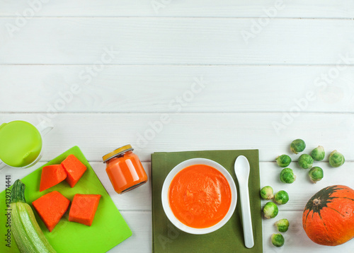 Puree from pumpkin in the plate and jar on white wooden background