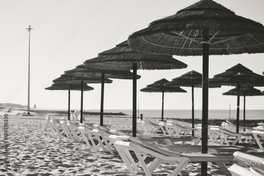Straw umbrellas on ocean beach in Algarve Portugal, sunny outdoors background