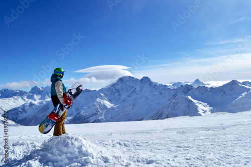 snowboarder standing with snowboard in the mountains.