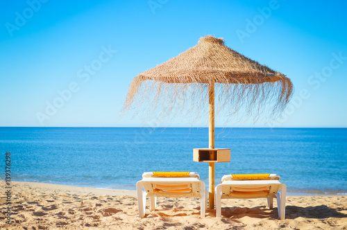 Fototapeta Naklejka Na Ścianę i Meble -  Straw umbrellas on ocean beach in Algarve Portugal, sunny outdoors background